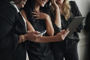 An image of three women in professional attire reading about executive brand building on a tablet device.