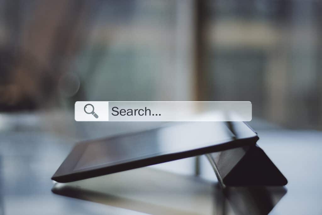 Search bar displayed over a tablet screen representing online search behavior, AI-powered discovery, and digital information seeking.