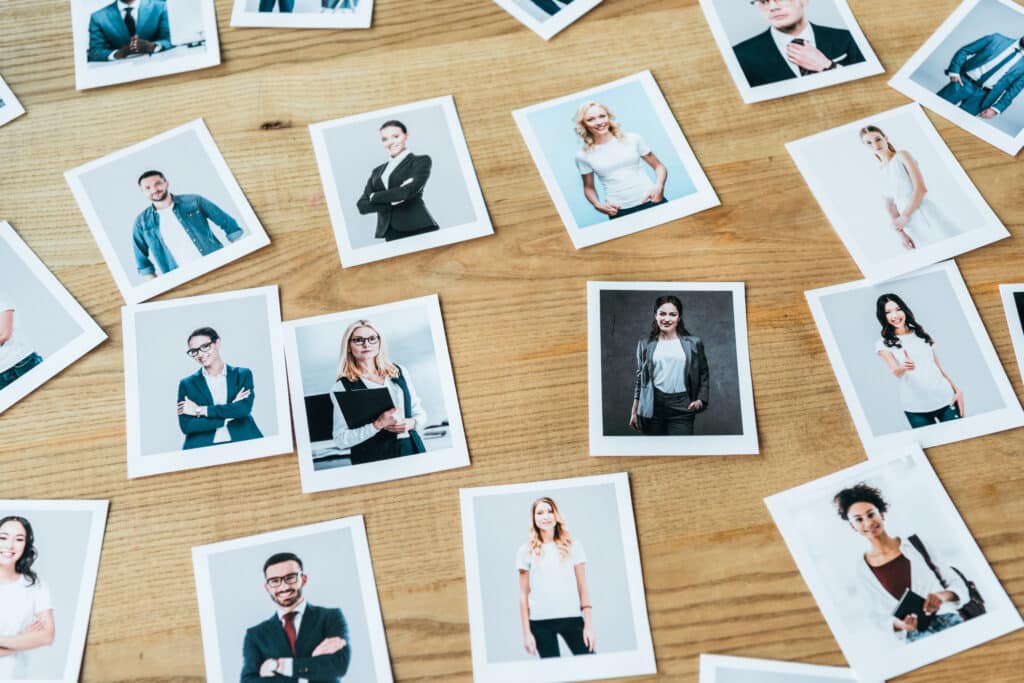 Collection of headshot photos of diverse professionals spread across a wooden table